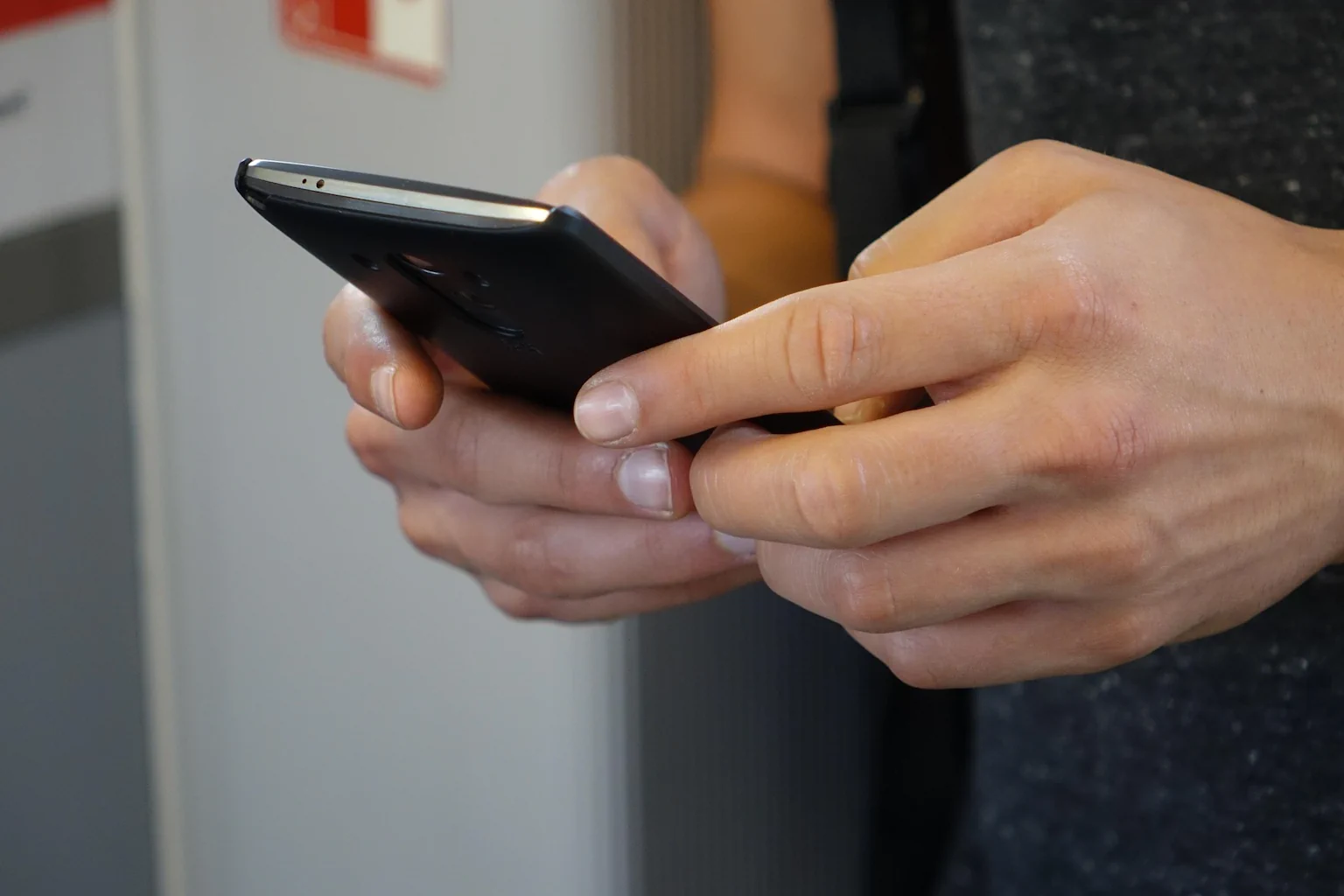 Gros plan sur une personne tenant son smartphone et lisant un message SMS